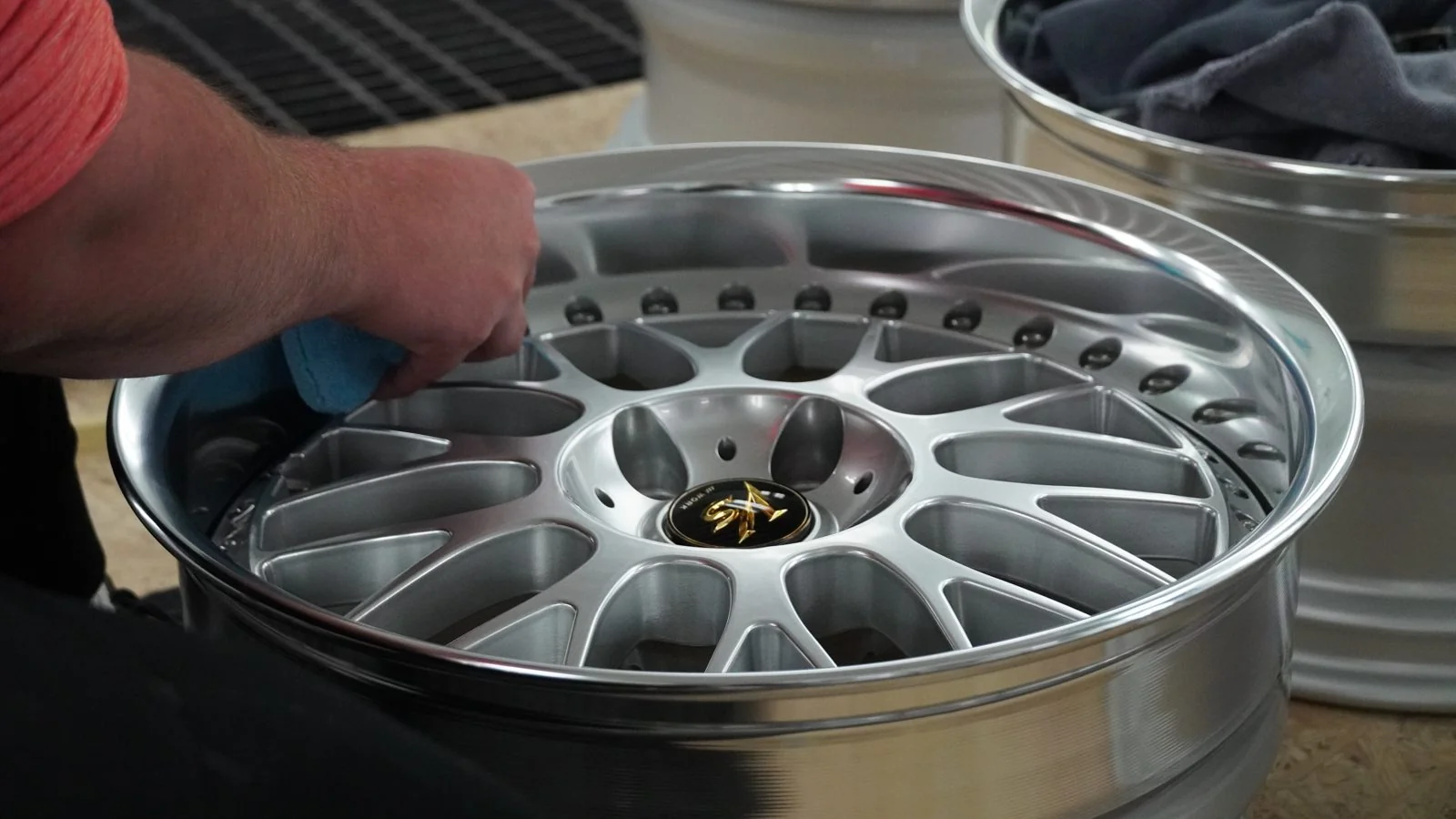 A detailer wiping down the face of a polished multi-spoke wheel